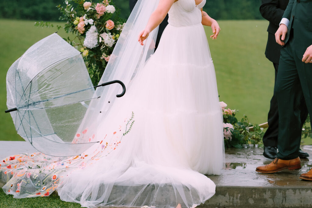 A bride throws her umbrella before the first kiss at a Spring wedding captured by Tags Photography at Meadows at Mossy Creek